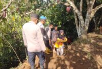 Kapolsek Putri Betung, Ipda Novrizal SH bersama personel membantu mengevakuasi seorang warga yang sedang menggendong bayi saat melintasi lokasi longsor susulan di Putri Betung, Senin (5/1/2026).