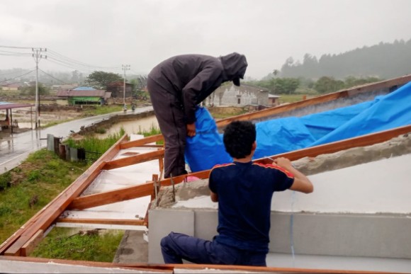 Personil Damkar sedang memasang tenda plastik pengganti seng diatap rumah warga, Rabu (15/4/2026)